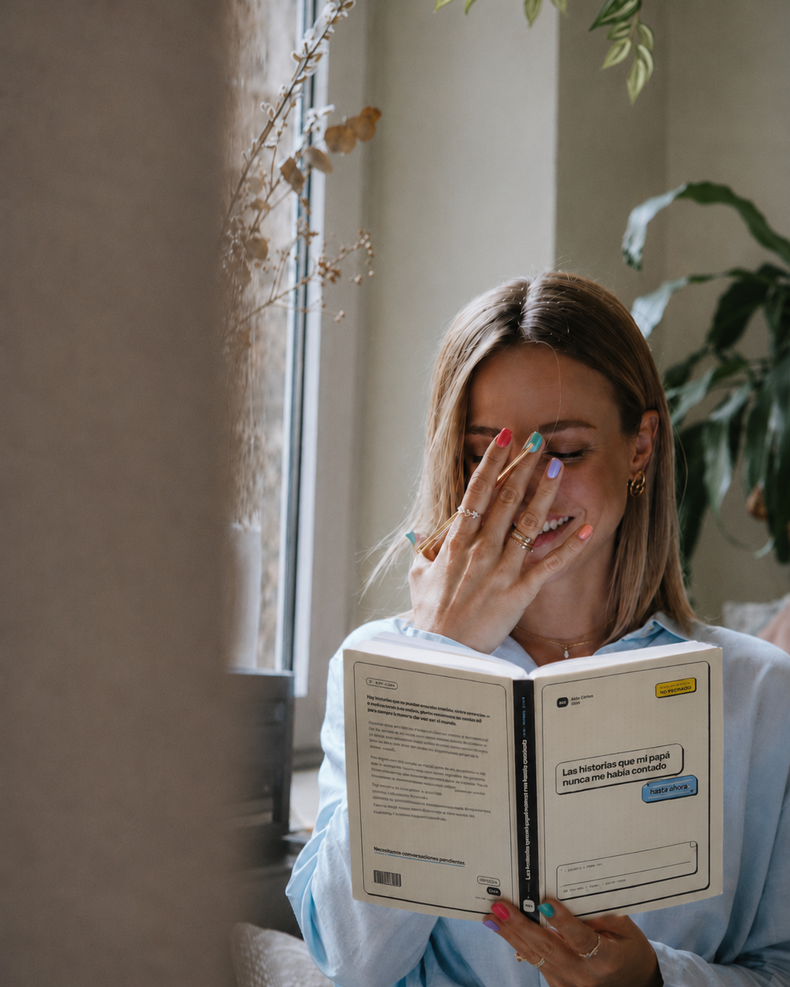 Mujer leyendo el libro Las historias de papá junto a una ventana.